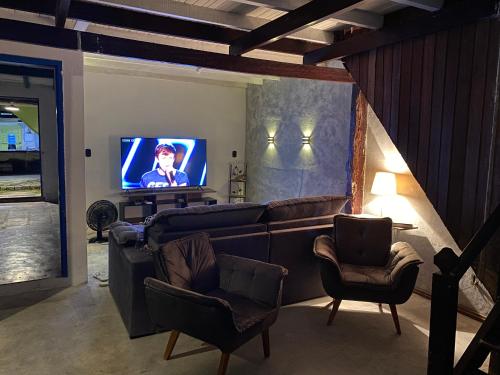 a living room with a couch and chairs and a television at Casa Lee Hostel in Paraty