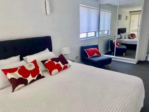 - une chambre dotée d'un grand lit avec des oreillers rouges et blancs dans l'établissement Absolute Hastings Street Noosa Suite, à Noosa Heads