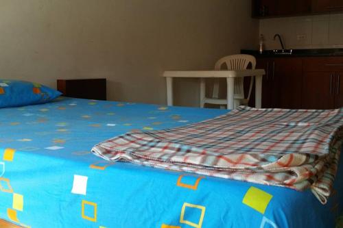 a bed with a blue comforter on top of it at Aparta-estudio amoblado 202, 2p, wifi in Socorro
