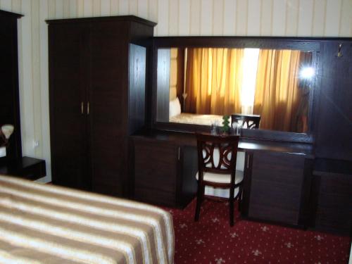 a bedroom with a bed and a desk and a mirror at Hotel Villa Ofir in Sandanski