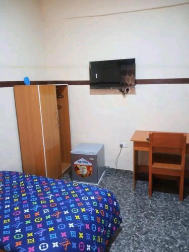 1 dormitorio con 1 cama, escritorio y TV en AMIGOS HOTEL, en Ibadán