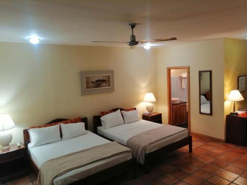 a bedroom with two beds and two lamps and a mirror at Apartotel Don Francisco in San José