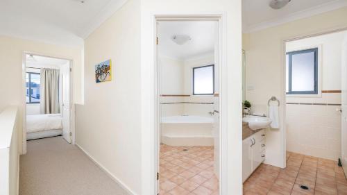 ein weißes Badezimmer mit einer Badewanne und einem Waschbecken in der Unterkunft Absolute Oceanfront Portovenere in Anna Bay