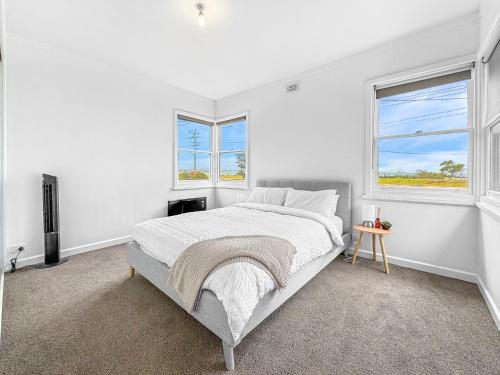 a white bedroom with a bed and two windows at No. 231 Waterfront in Portland