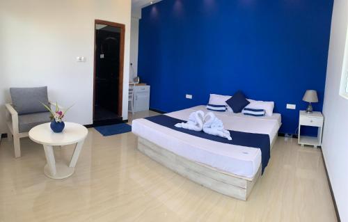 a blue bedroom with a bed and a table at Anukama Resort in Nilaveli