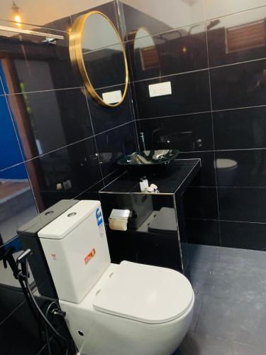 a bathroom with a white toilet and a mirror at Anukama Resort in Nilaveli