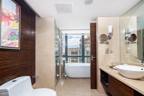 a bathroom with a tub and a toilet and a sink at Newyantai Hotel Hainan in Haikou