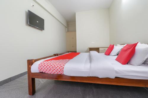 sypialnia z dużym łóżkiem z białymi i czerwonymi poduszkami w obiekcie Appas Residency w mieście Ambalavayal