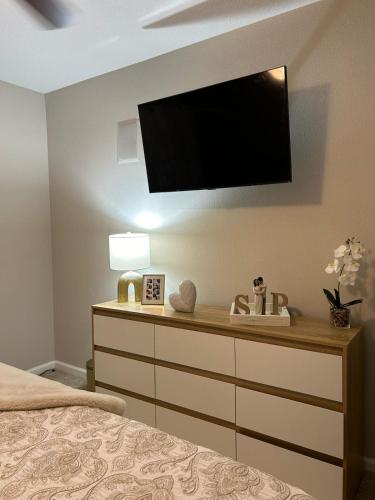 Coral gables apartment في ميامي: غرفة نوم مع خزانة مع تلفزيون على الحائط