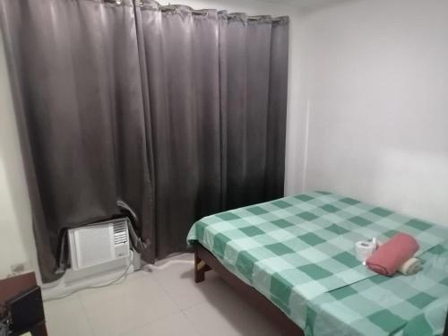 a bedroom with a bed with a green and white checkered blanket at Birchtower studio in Manila