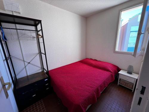 - une petite chambre avec un lit rouge et une fenêtre dans l'établissement Appartement coquet avec parking, 4 couchages - FR-1-784-4, à Gruissan