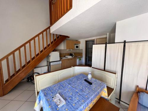 une salle à manger avec une table et un escalier dans l'établissement Maison T3 avec mezzanine et garage, proche plage, idéale pour 6 pers. avec terrasse et équipements complets - FR-1-784-1, à Gruissan