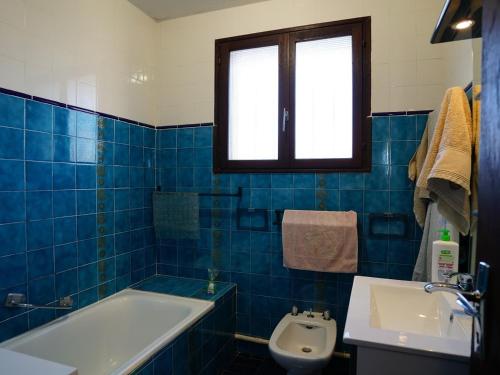 La salle de bains est pourvue de carrelage bleu, d'une baignoire et d'un lavabo. dans l'établissement Chalet individuel 6-7 pers avec barbecue, terrasse, parking, animaux admis à Gruissan - FR-1-784-18, à Gruissan