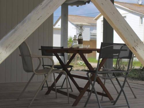 - une table en bois et 2 chaises sur une terrasse couverte dans l'établissement Chalet à 200m de la plage - Terrasse, TV, Parking, 4 Couchages - Option Étages, 12 Couchages - FR-1-784-22, à Gruissan