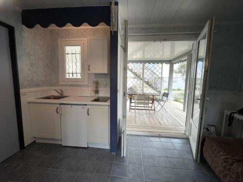 une cuisine avec un évier et une porte donnant sur une terrasse. dans l'établissement Chalet à 200m de la plage - Terrasse, TV, Parking, 4 Couchages - Option Étages, 12 Couchages - FR-1-784-22, à Gruissan