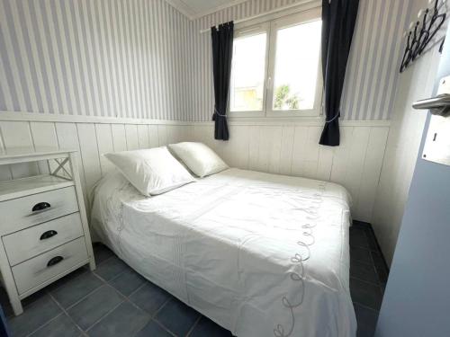 une petite chambre avec un lit et une fenêtre dans l'établissement Chalet à 200m de la plage - Terrasse, TV, Parking, 4 Couchages - Option Étages, 12 Couchages - FR-1-784-22, à Gruissan