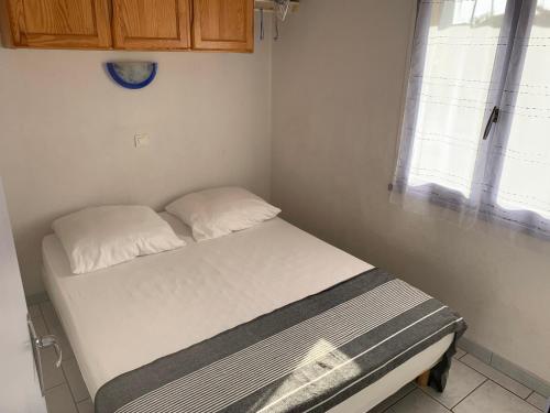 un petit lit dans une chambre avec une fenêtre dans l'établissement Chalet cosy à 400m de la plage avec terrasse et parking - 2 chambres, 4 pers. - FR-1-784-17, à Gruissan
