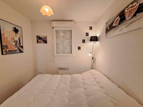 un grand lit blanc dans une chambre avec une fenêtre dans l'établissement Appartement 2 pièces avec terrasse, parking et accès direct à la plage à Marseillan - FR-1-326-816, à Marseillan