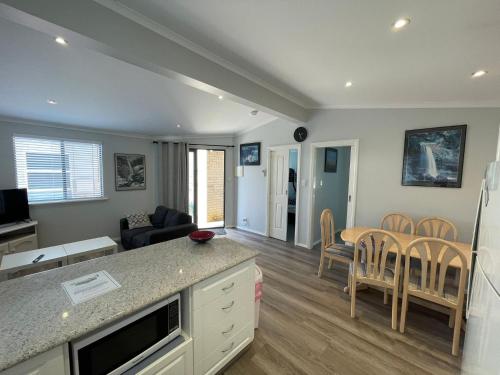 a kitchen and living room with a table and chairs at Budgie Smuggler - Cabin 96 Geographe Bay Holiday Park in Broadwater