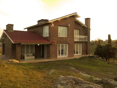 una gran casa de ladrillo en una colina de hierba en Casa de Campo El Duraznillo en Tandil