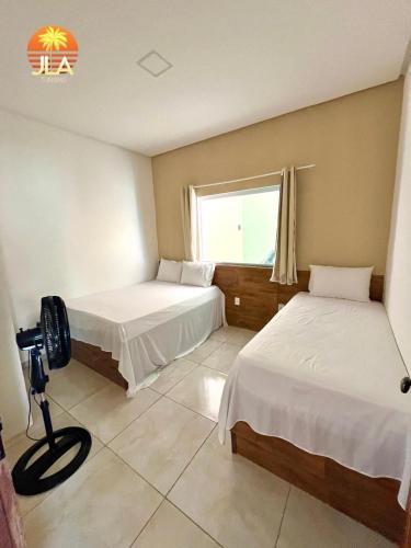 een hotelkamer met 2 bedden en een raam bij Casa em Paripueira, conforto e privacidade in Paripueira