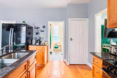 a kitchen with a sink and a refrigerator at The Tremont Emerald - By Christmas Story House - Historic Charm & Modern Comfort Near Downtown With Parking, 300MB Wifi & Self Check-In in Cleveland