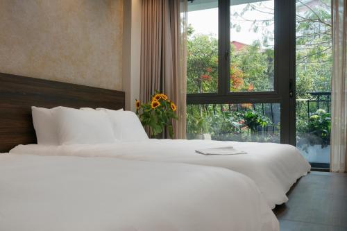 two white beds in a bedroom with a window at Brilliant Nature Suites & Spa in Hanoi
