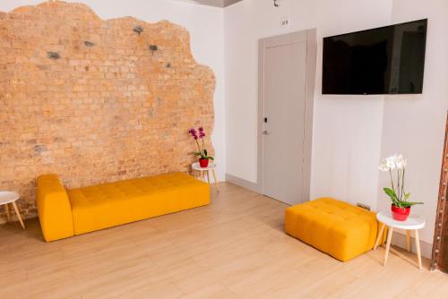 salon z żółtą kanapą i ceglaną ścianą w obiekcie Hostal Juliette-Gran Vía w Madrycie