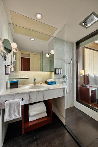 a bathroom with a large sink and a shower at Mövenpick Hotel Hanoi Centre in Hanoi