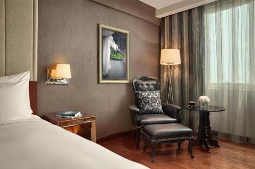 a hotel room with a bed and a chair at Mövenpick Hotel Hanoi Centre in Hanoi