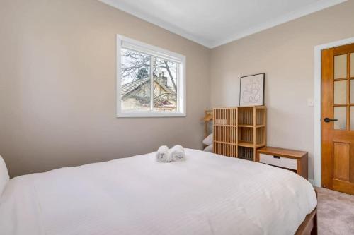 Cosy & Modern Mountain Getaway Katoomba في كاتومبا: غرفة نوم بسرير ابيض كبير ونافذة
