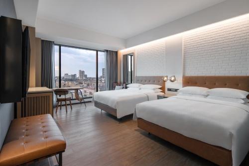 a hotel room with two beds and a table at Four Points by Sheraton Taipei Bali in Bali