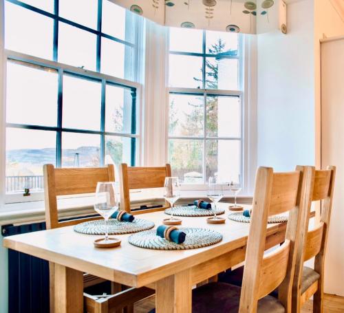 a dining room with a table with chairs and windows at Gleddoch Coach House in Langbank