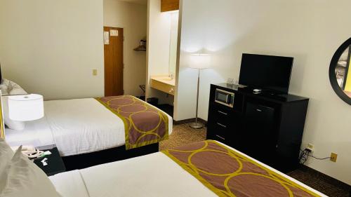 a hotel room with two beds and a flat screen tv at Forest City Inn in Forest City