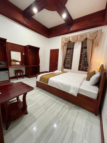 a bedroom with a large bed and a desk at PhaiLin Hotel in Luang Prabang