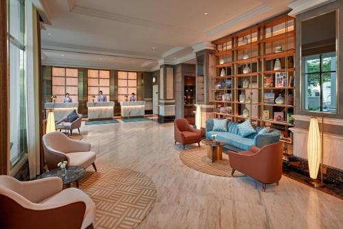 a living room with a blue couch and chairs at Mövenpick Hotel Hanoi Centre in Hanoi