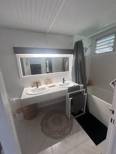a bathroom with two sinks and a mirror and a tub at Studio Sagesse d’Elodie. in Le Moule