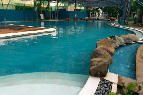 a large swimming pool with blue water and rocks at Luxury Resort Condo in Pasig FastWifiPoolSmartLock in Manila