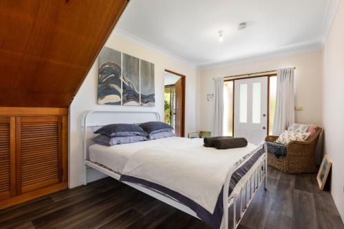 - une chambre avec un grand lit blanc et des oreillers bleus dans l'établissement Breeze on Barclay, à Gerringong