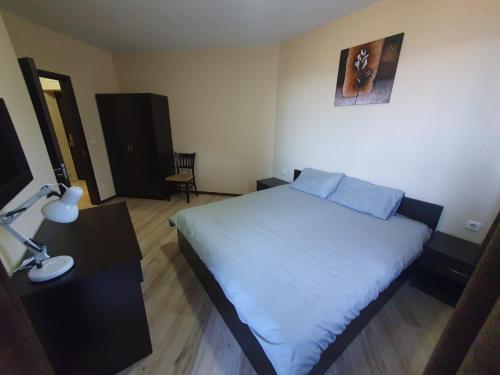 ein Schlafzimmer mit einem Bett und einem Schreibtisch mit einer Lampe in der Unterkunft Dream Holiday apartment in Bansko