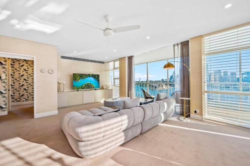 ein Wohnzimmer mit einem großen Sofa und einem großen Fenster in der Unterkunft Vivid Sydney Landmark Views from Luxury 2Bd Apt in Sydney