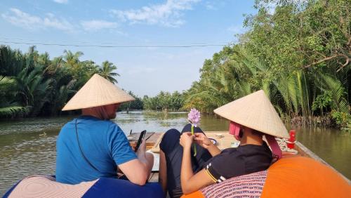 two people in hats on a boat on a river at Comfy Riverside Mekong homestay Ben Tre in Ấp Phú Hòa (3)