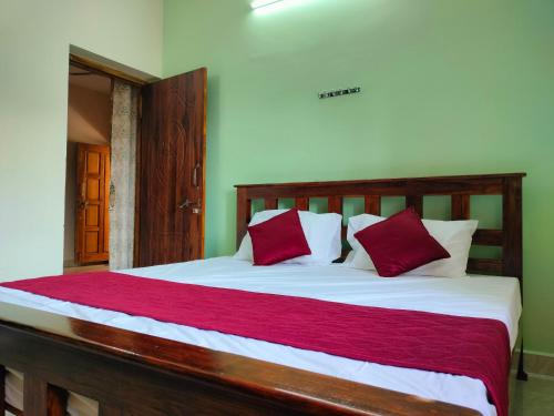 AthmA ArunA - Homestay Tiruvannamalai في تيروفانمالي: غرفة نوم بسرير كبير ومخدات حمراء وبيضاء