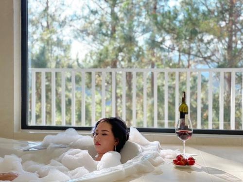 een klein meisje liggend in een bad met een fles wijn bij Romeo & Juliet Dalat Resort in Da Lat