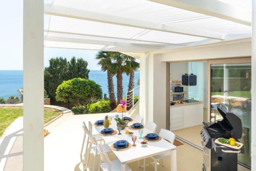 a white dining room with a table and a view of the ocean at Caiammari Boutique Hotel & Spa in Syracuse