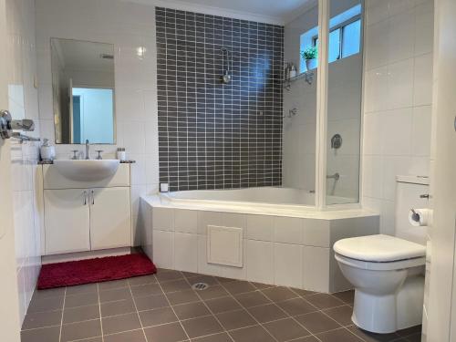 a bathroom with a tub and a toilet and a sink at Qbn Cracker: 2BR, 2BA, 2 secure b/ ment car parks in Queanbeyan