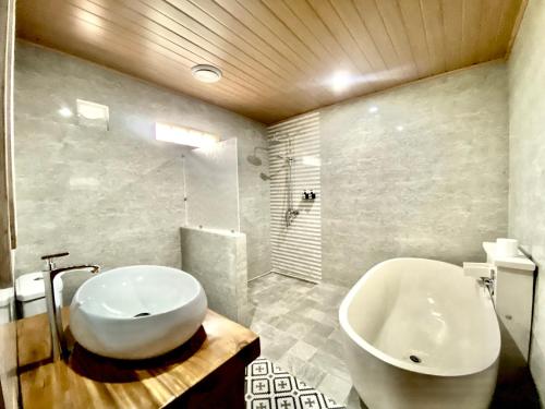 a bathroom with a large white tub and a sink at Adil Villa & Resort in Ubud