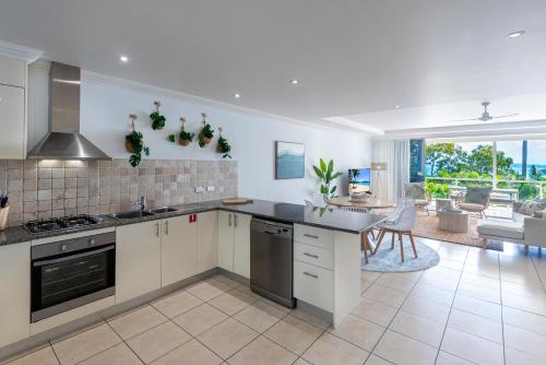 a kitchen with white appliances and a living room at Blue Water Views on Hamilton Island by HIHA in Hamilton Island