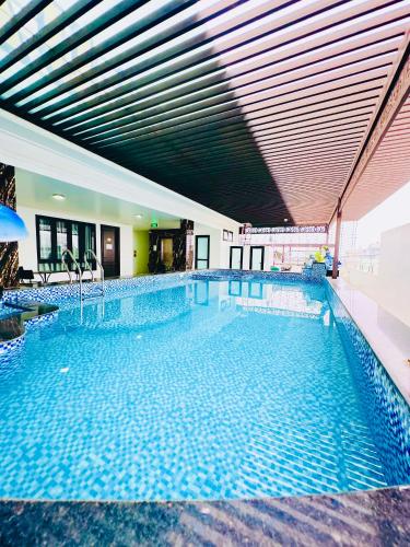 a large swimming pool with blue water in a building at Khách Sạn Châu Long FLC Sầm Sơn in Sầm Sơn