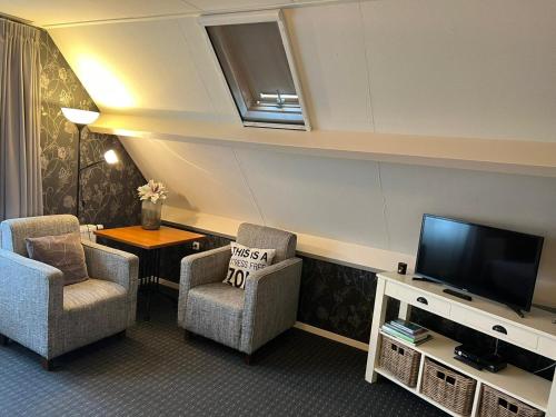 a living room with two chairs and a flat screen tv at B&B 't Landschap in Boelenslaan